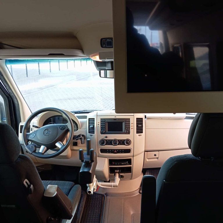 Durch Hinweis durch das Neue Wege Kompetenzzentrum Innenansicht eines Rollstuhlmobil mit Lenkrad, Monitor und ausgestatteter Konsole.